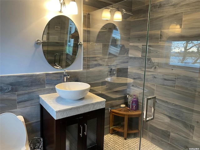 bathroom with vanity, a shower with shower door, and tile walls