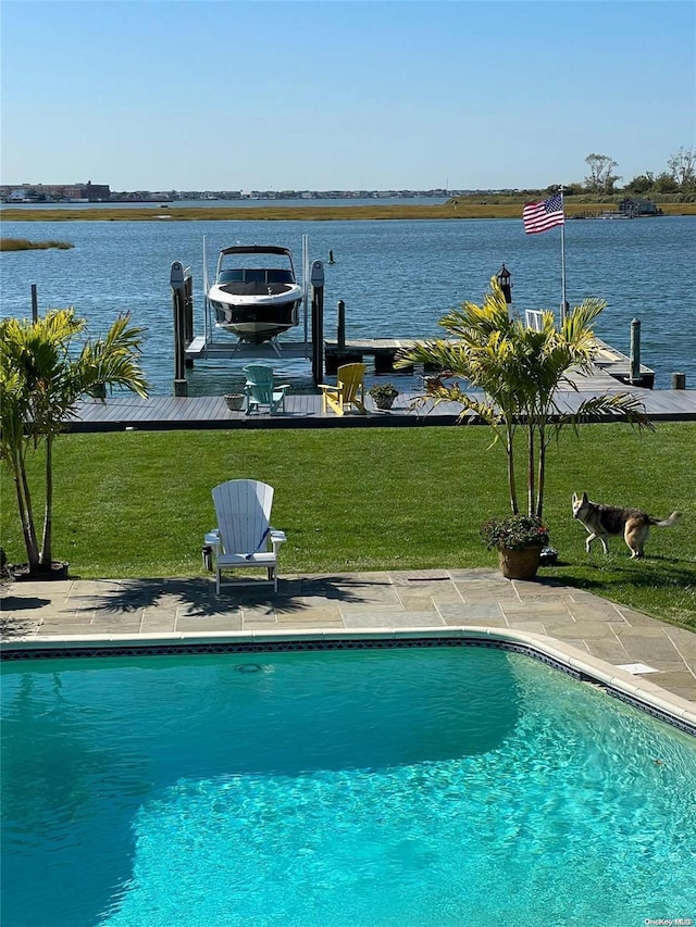 view of pool with a water view, a lawn, and a dock