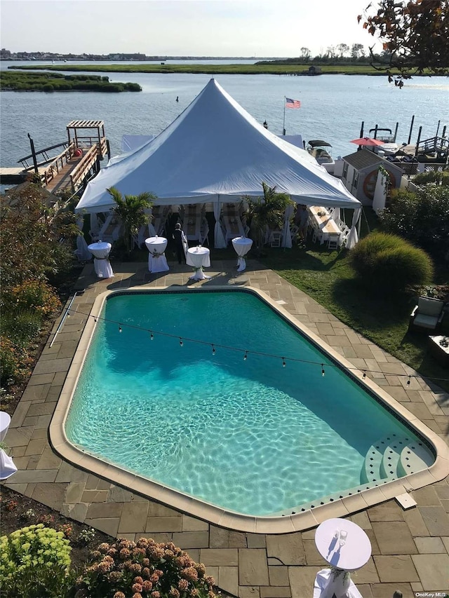 view of swimming pool featuring a patio and a water view