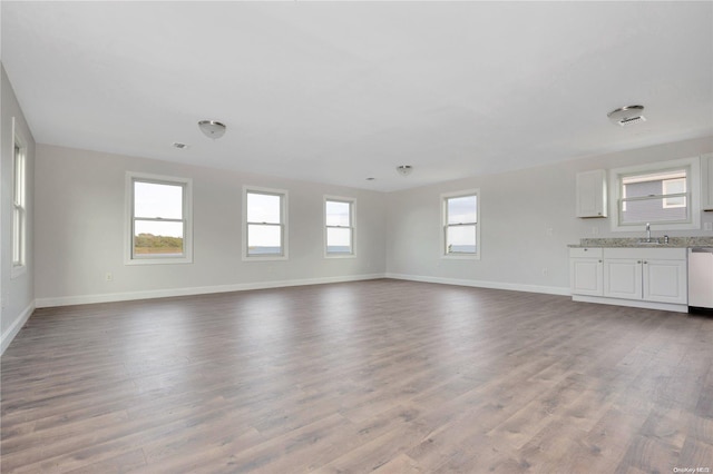 unfurnished living room featuring light hardwood / wood-style flooring, a wealth of natural light, and sink