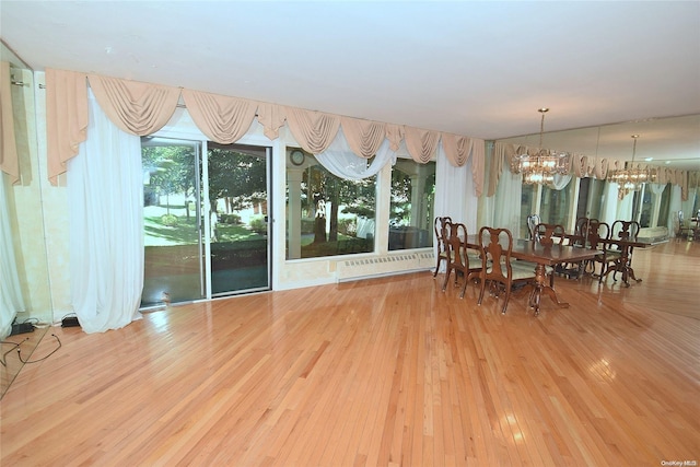 unfurnished dining area with baseboard heating, hardwood / wood-style floors, and an inviting chandelier