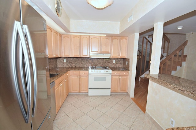 kitchen with light tile patterned floors, light brown cabinetry, backsplash, and appliances with stainless steel finishes