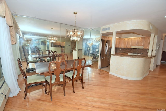 dining space with light wood-type flooring and an inviting chandelier