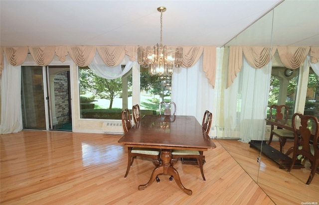 dining space with wood-type flooring, an inviting chandelier, and a healthy amount of sunlight