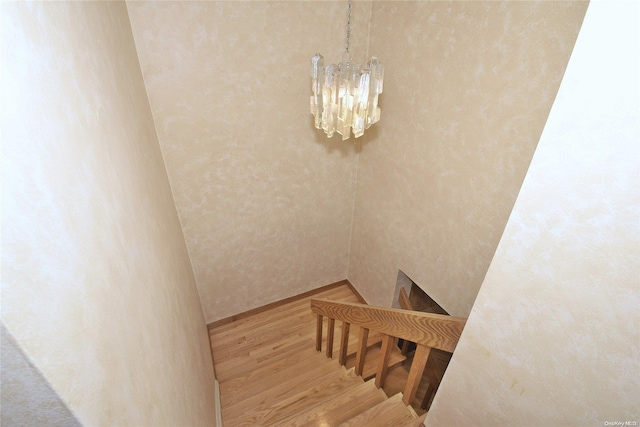 stairs featuring hardwood / wood-style floors and a chandelier