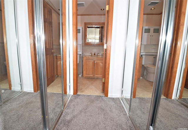 hallway featuring light colored carpet, crown molding, and sink