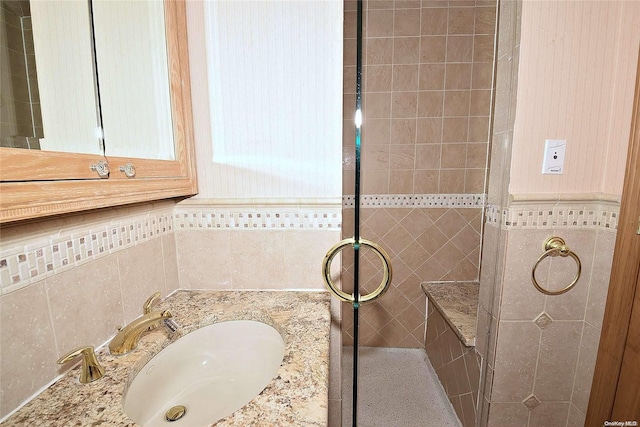 bathroom with vanity, tiled shower, and tile walls