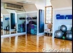 workout area with hardwood / wood-style floors and a wall mounted AC