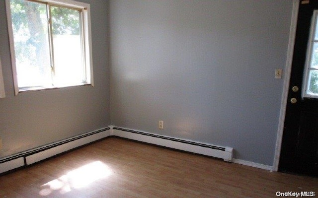 spare room with wood-type flooring and a baseboard radiator