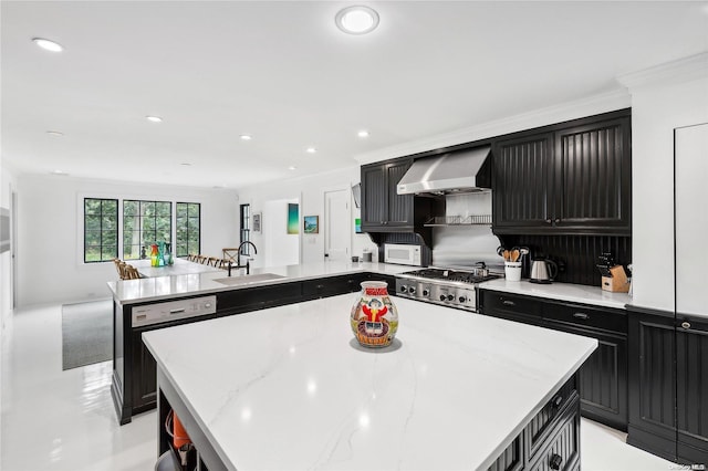 kitchen featuring appliances with stainless steel finishes, a center island, wall chimney exhaust hood, and sink