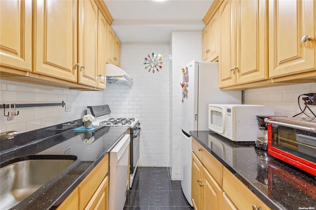 kitchen featuring dark stone counters, sink, stainless steel gas stove, light brown cabinetry, and tasteful backsplash