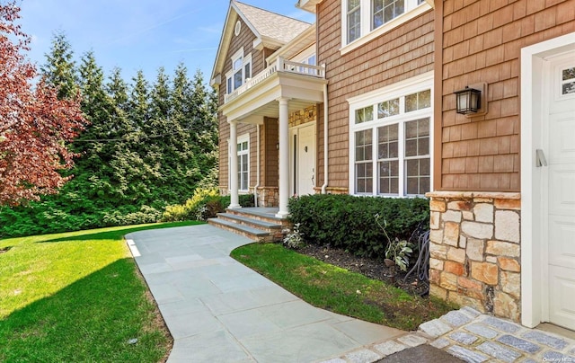 entrance to property with a balcony and a lawn