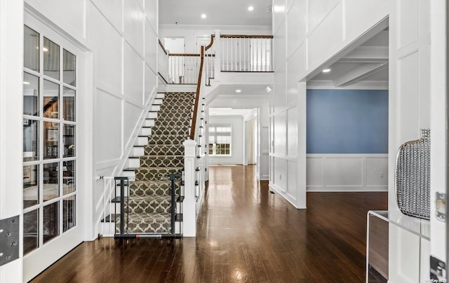 foyer with beam ceiling, ornamental molding, and dark wood-type flooring