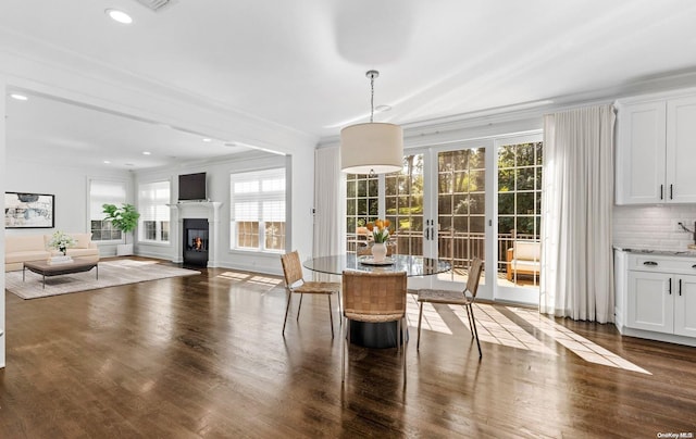 unfurnished dining area featuring a healthy amount of sunlight, dark hardwood / wood-style flooring, crown molding, and french doors