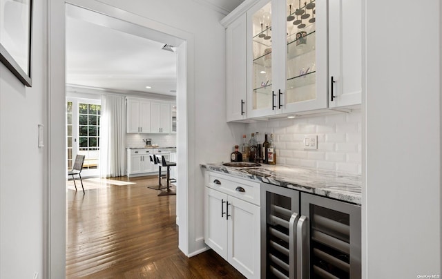 bar with white cabinetry, dark wood-type flooring, tasteful backsplash, wine cooler, and light stone counters