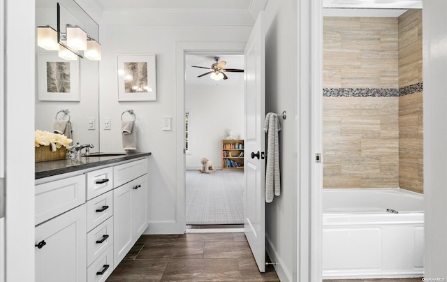 bathroom featuring ceiling fan, a bathtub, vanity, and ornamental molding