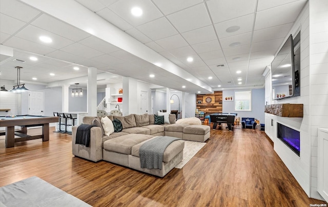 living room featuring wood-type flooring, a paneled ceiling, and pool table