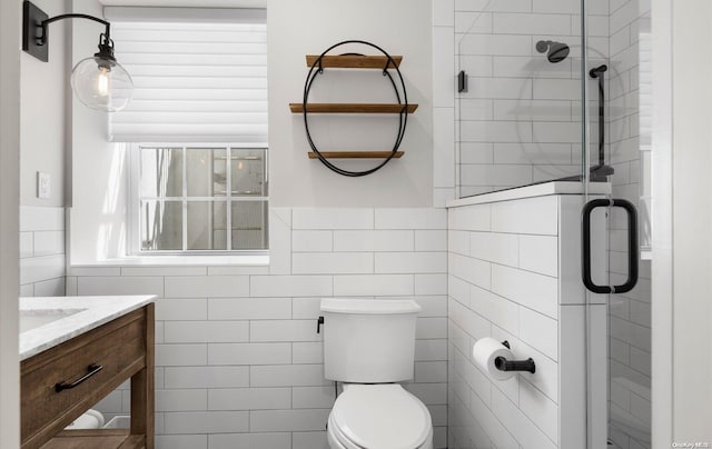 bathroom featuring vanity, a shower with shower door, tile walls, and toilet