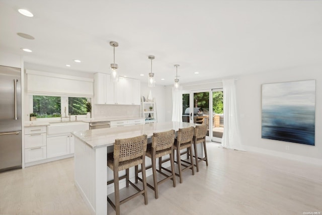 kitchen with white cabinets, a wealth of natural light, a kitchen island, and decorative light fixtures