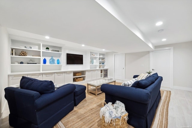 living room with built in shelves and light hardwood / wood-style floors