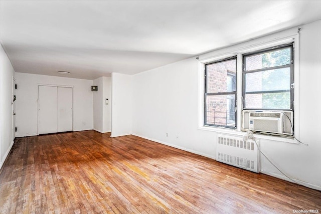 empty room featuring hardwood / wood-style floors, radiator, and cooling unit