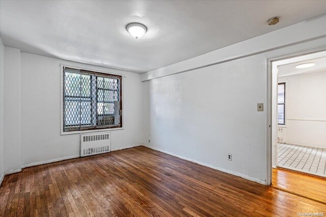 empty room featuring radiator heating unit and dark wood-type flooring