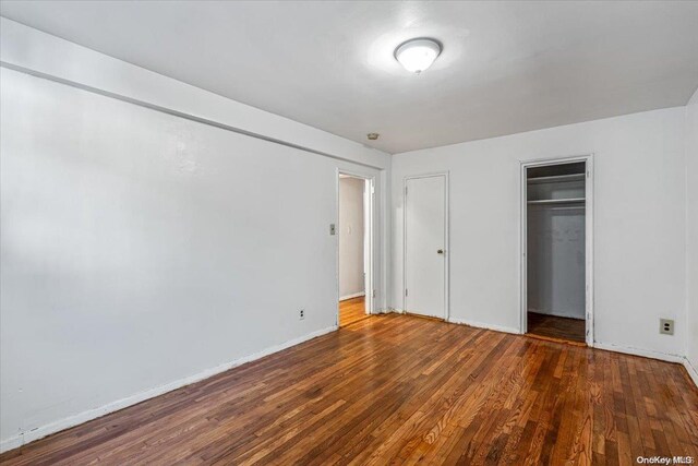 unfurnished bedroom with dark hardwood / wood-style flooring and a closet