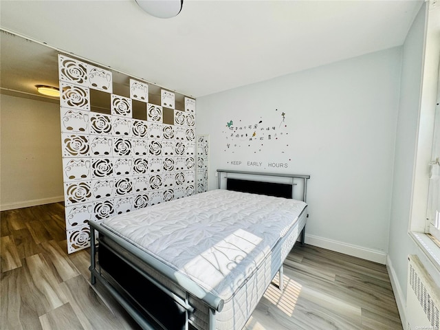 bedroom featuring radiator heating unit and hardwood / wood-style floors