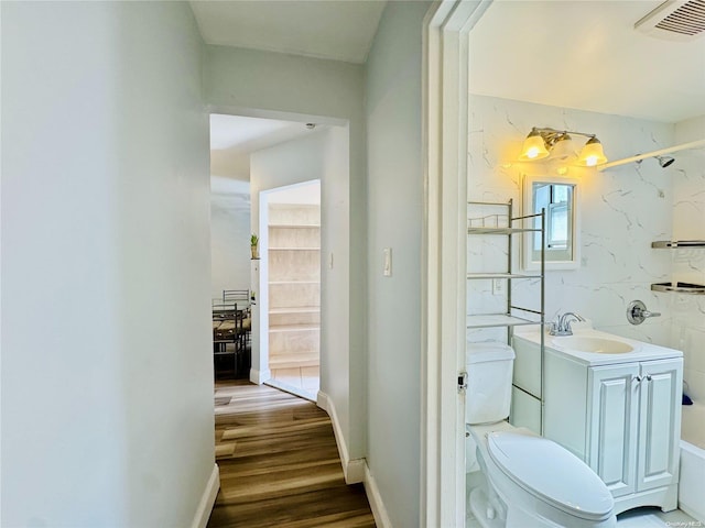 bathroom featuring wood-type flooring, vanity, an inviting chandelier, and toilet