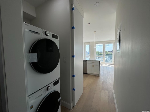 laundry area featuring stacked washer / drying machine and light hardwood / wood-style floors