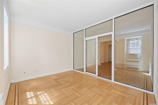 unfurnished bedroom with radiator heating unit, light parquet flooring, and a closet