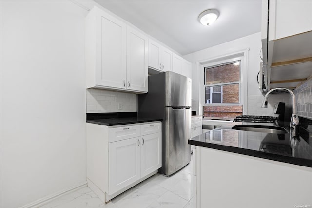 kitchen with white cabinets, sink, decorative backsplash, stainless steel fridge, and range