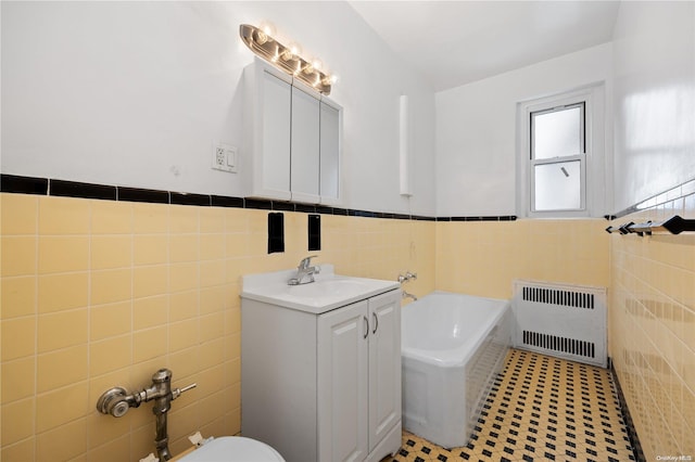 bathroom with vanity, radiator, tile patterned flooring, a tub to relax in, and tile walls