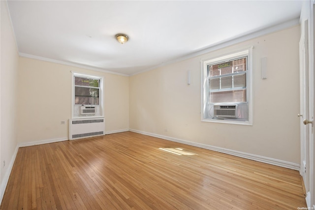 empty room featuring radiator heating unit, cooling unit, ornamental molding, and light hardwood / wood-style flooring