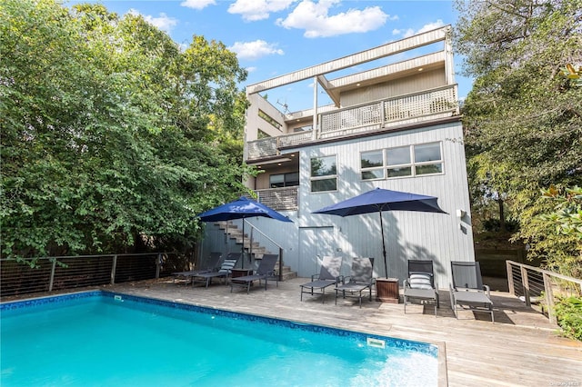 rear view of house featuring a balcony and a fenced in pool