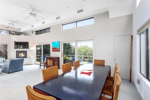 carpeted dining area featuring ceiling fan and a high ceiling