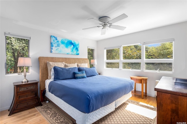 bedroom featuring ceiling fan, light wood-type flooring, and multiple windows