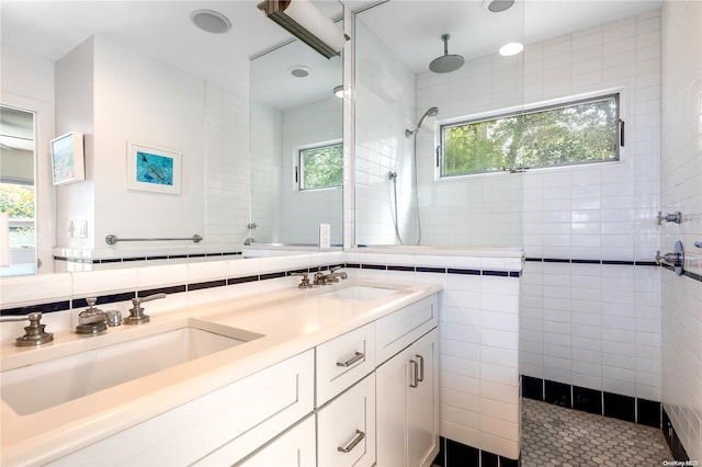 bathroom with tile patterned flooring, vanity, a tile shower, and tile walls