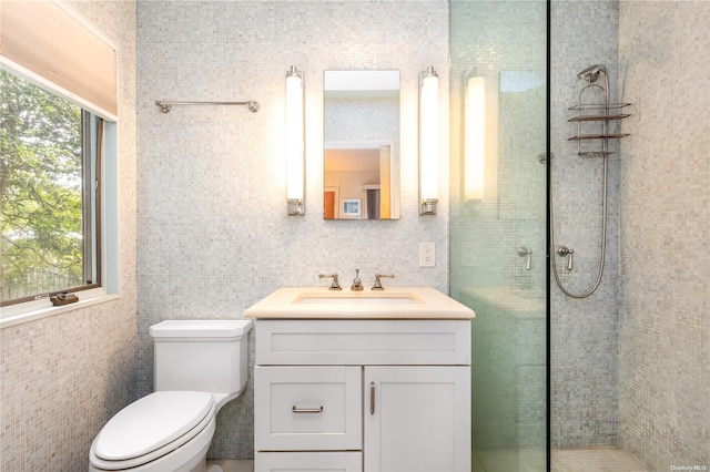 bathroom featuring vanity, a healthy amount of sunlight, toilet, and tile walls