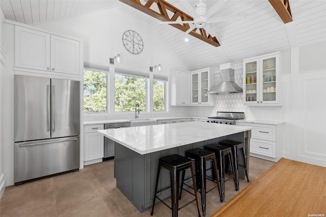 15 Hill Side Ln, East Hampton, NY 11937 - kitchen with stainless steel appliances, wall chimney range hood, a wooden ceiling with exposed beams, tasteful backsplash, and a kitchen breakfast bar