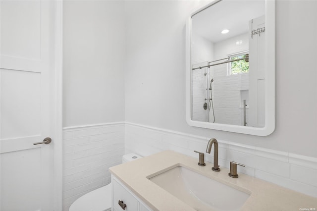 bathroom with vanity, toilet, walk in shower, and tile walls