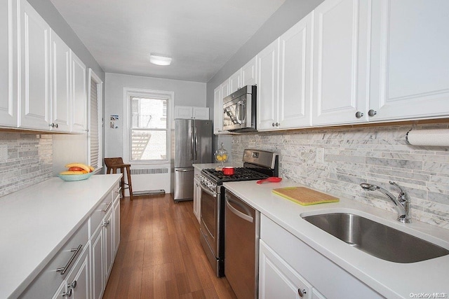 kitchen with dark wood-type flooring, radiator, sink, appliances with stainless steel finishes, and white cabinetry