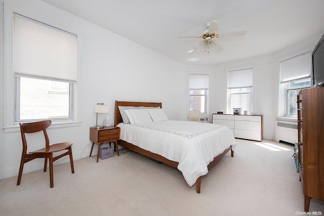 carpeted bedroom featuring radiator, ceiling fan, and multiple windows