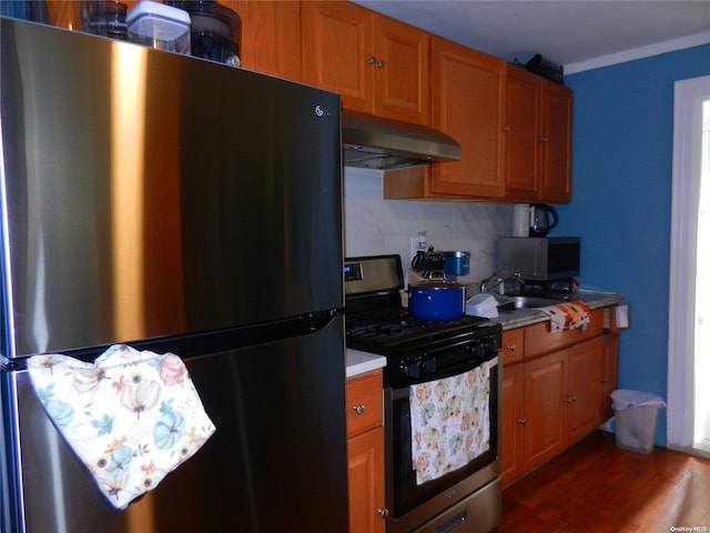 kitchen featuring appliances with stainless steel finishes, sink, decorative backsplash, crown molding, and dark wood-type flooring