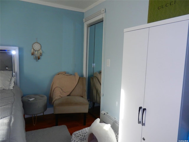 living area with crown molding, wood-type flooring, and a baseboard heating unit