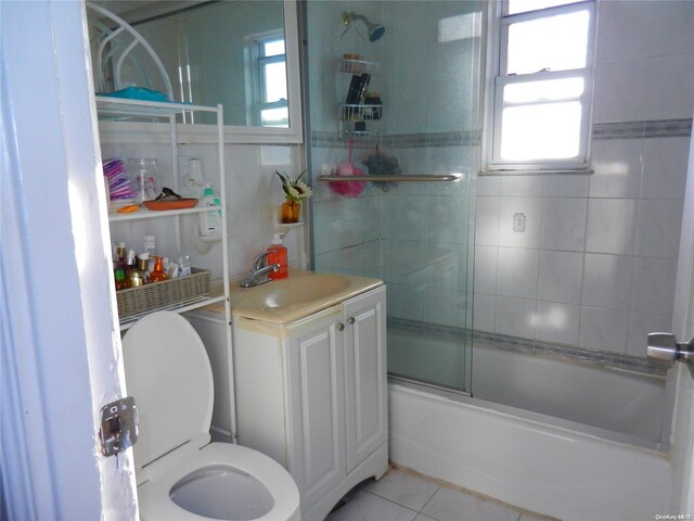 full bathroom with combined bath / shower with glass door, toilet, tile patterned flooring, and a wealth of natural light