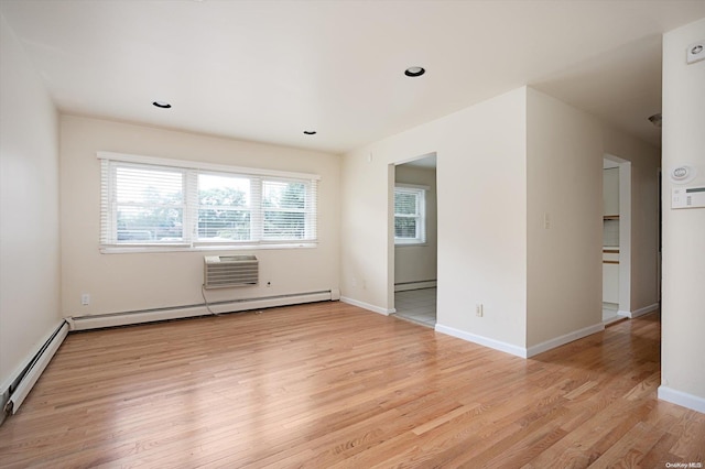 empty room with a wall unit AC, a baseboard radiator, and light hardwood / wood-style flooring