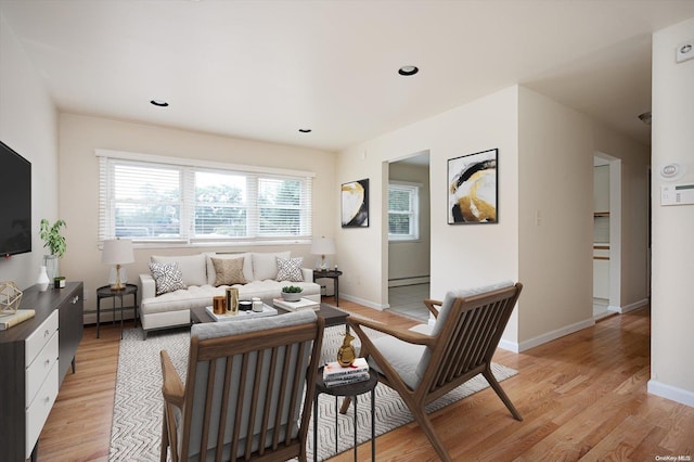 living room with a baseboard heating unit and light hardwood / wood-style flooring