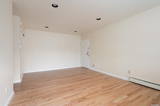 spare room featuring light wood-type flooring and baseboard heating