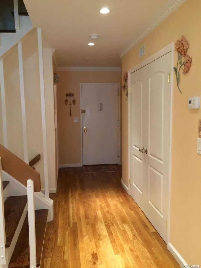 hallway with light wood-type flooring and ornamental molding